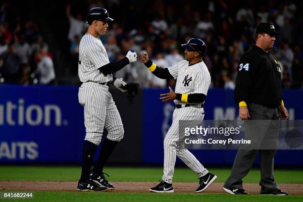 Aaron Judge fist bumps first base coach Tony Pea both of the New York Yankees near second base after a double against the Boston Red Sox during the...