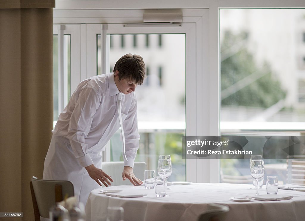 Waiter sets flatware in precise positions