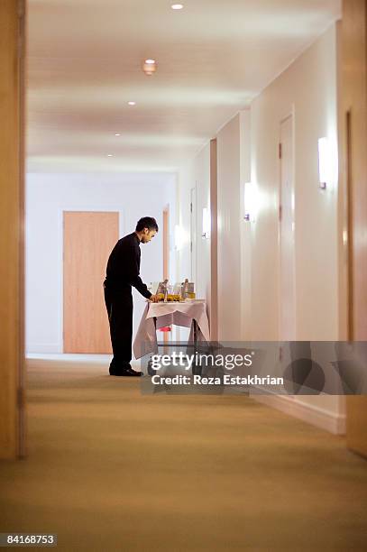 room service waiter by cart in hotel corridor - serviços de limpeza imagens e fotografias de stock