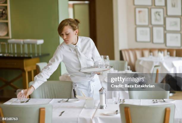 waitress sets out water glasses in restaurant - empregada de mesa imagens e fotografias de stock