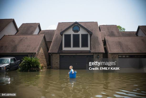 Jenna Fountain carries a bucket down Regency Drive to try to recover items from their flooded home in Port Arthur, Texas, September 1, 2017....