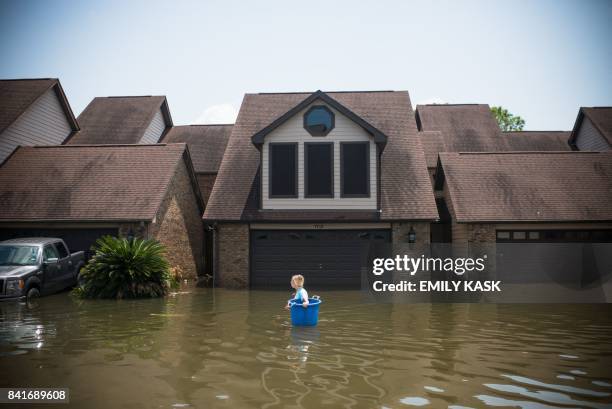 Jenna Fountain carries a bucket down Regency Drive to try to recover items from their flooded home in Port Arthur, Texas, September 1, 2017....