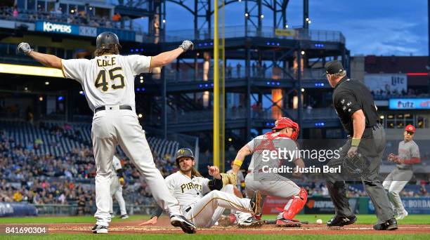 Gerrit Cole of the Pittsburgh Pirates reacts as John Jaso slides safely past Stuart Turner of the Cincinnati Reds to score in the second inning...
