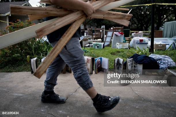 Worker carries water damaged wood as he passes salvaged personal items from a once flooded home as residents begin the recovery process from...