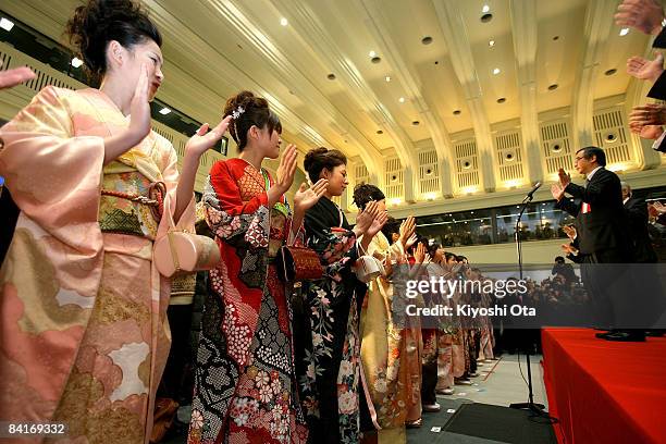 Women dressed in kimonos applaud as they attend the opening ceremony to celebrate the start of the year's trading at the Tokyo Stock Exchange on...