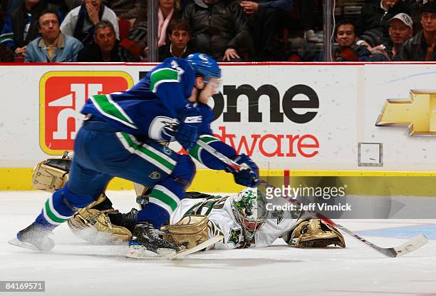 Marty Turco of the Dallas Stars poke checks Alexander Edler of the Vancouver Canucks during their game at General Motors Place on January 4, 2009 in...