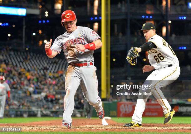 Scooter Gennett of the Cincinnati Reds scores on a wild pitch by Dovydas Neverauskas of the Pittsburgh Pirates in the eighth inning during the game...