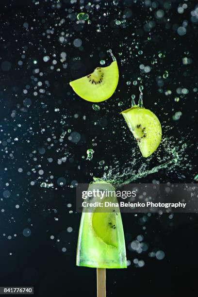 popsicle with fresh kiwi fruit on a dark background, dynamic shot with action, splash, water drops and bokeh. - flying kiwi stock pictures, royalty-free photos & images