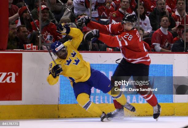 Patrice Cormier of Team Canada checks Carl Gustafsson of Team Sweden into the boards during the 2009 IIHF World Junior Championships held at...