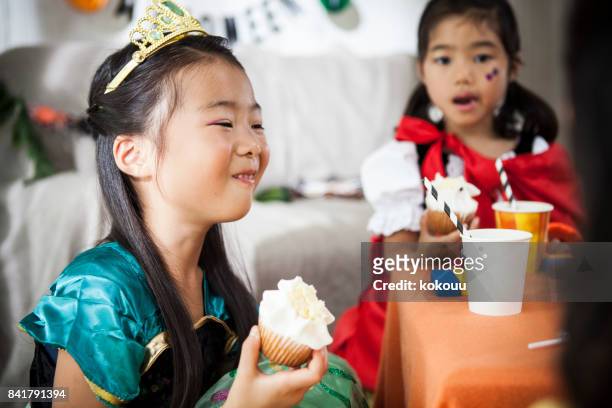 two girls eat cupcakes at a halloween party. - princess party stock pictures, royalty-free photos & images