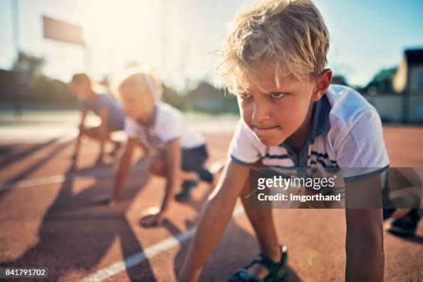 bambini che si preparano per la gara di corsa su pista - determinazione foto e immagini stock