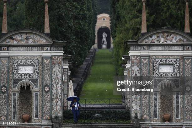 An attendee holds an umbrella as he arrives at hotel Villa d'Este during the Ambrosetti Forum in Cernobbio, Italy, on Saturday, Sept. 2, 2017. Policy...