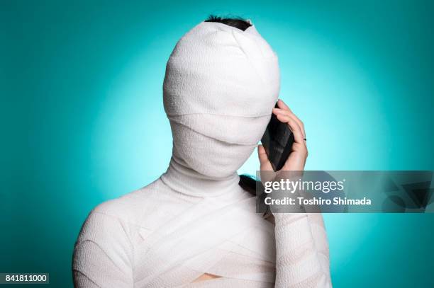 bandage wrapped woman holding a mobile phone - bandage stock pictures, royalty-free photos & images