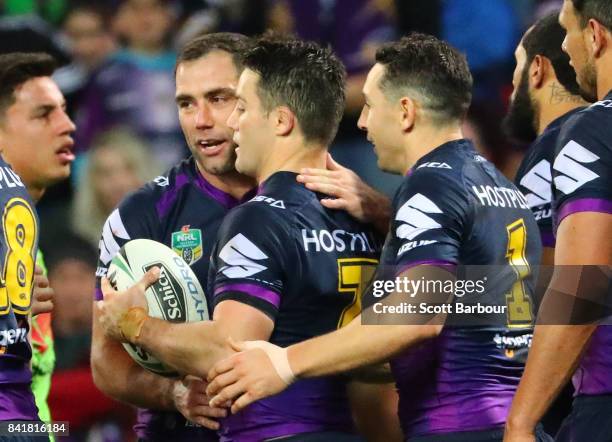 Cooper Cronk of the Storm is congratulated by Cameron Smith and Billy Slater after scoring a try which was later disallowed by the video referee for...