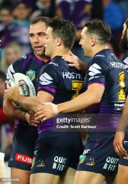 Cooper Cronk of the Storm is congratulated by Cameron Smith and Billy Slater after scoring a try which was later disallowed by the video referee for...