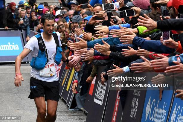 Second-placed Spanish athlete and former Mount Blanc Ultra Trail winner, Kilian Jornet, greets supporters as he runs towards the finish line of the...