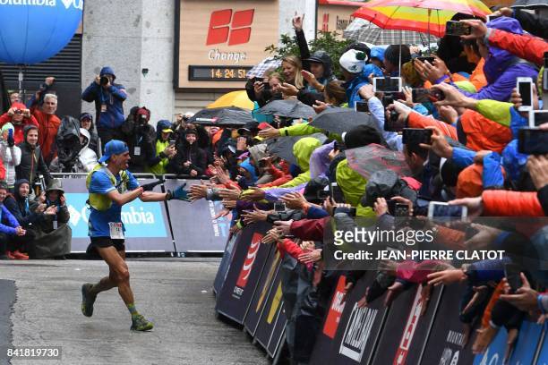 Third-placed US athlete Tim Tollefson greets supporters as he runs towards the finish line of the 15th edition of the Mount Blanc Ultra Trail , a 170...