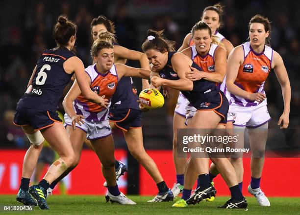 Emma Kearney of Victoria handballs whilst being tackled by Katie Brennan of the Allies during the AFL Women's State of Origin match between Victoria...