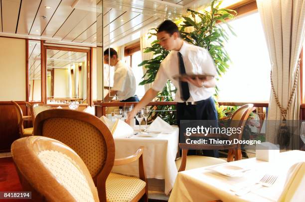 waiter laying the table in restaurant of cruise sh - camarero fotografías e imágenes de stock