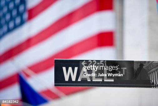 Sign on Wall Street and American flag. Sign on Wall Street and American flag.