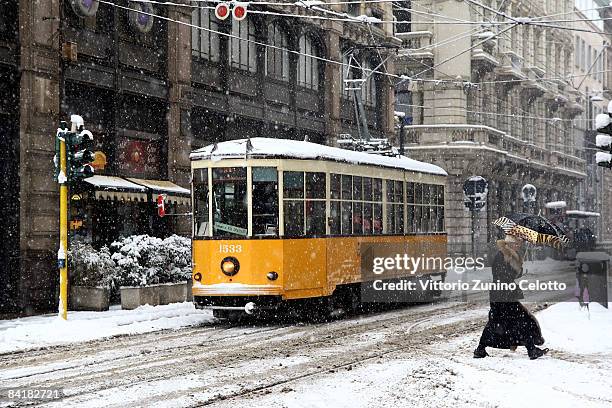 Woman protects herself from the snow as a tram passes by on January 6, 2009 in Milan, Italy. Parts of northern and central Italy are experiencing...