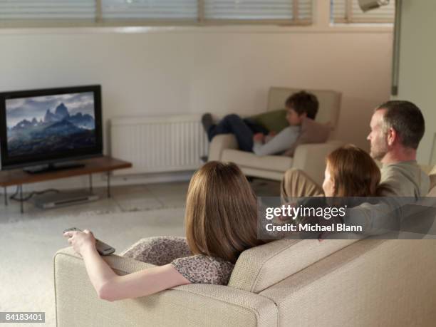 family sat on sofa at home watching tv - family tv stock-fotos und bilder