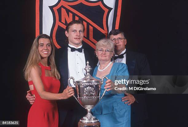 Canadian ice hockey player Adam Graves and his family pose in front of the National Hockey League logo with the King Clancy Memorial Trophy, 1994....