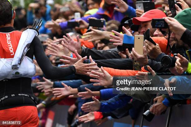 French athlete Francois D'Haene greets supporters as he runs towards the finish line of the 15th edition of the Mount Blanc Ultra Trail , a 170 km...