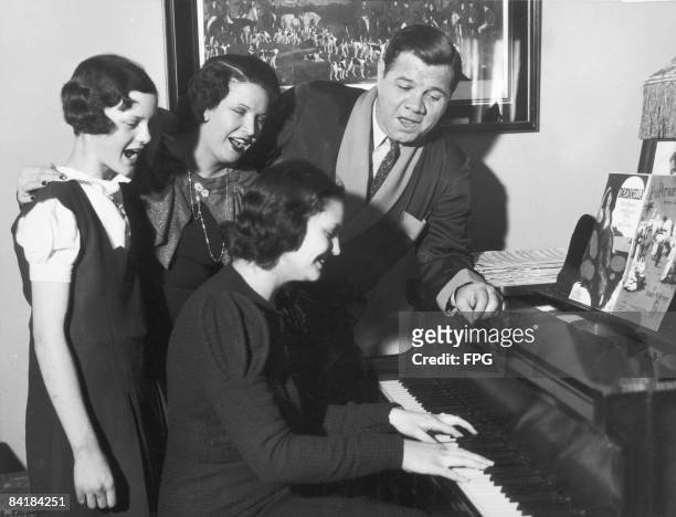 American baseball player Babe Ruth sings with his family as they celebrate his 40th birthday, New York, New York, February 7, 1940. At the piano is...