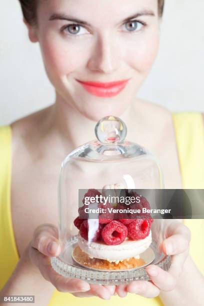 woman holding a raspberries cake under a bell jar. - bell jar stockfoto's en -beelden