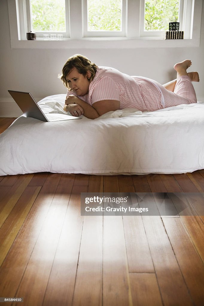 Woman Looking at Computer in Bed