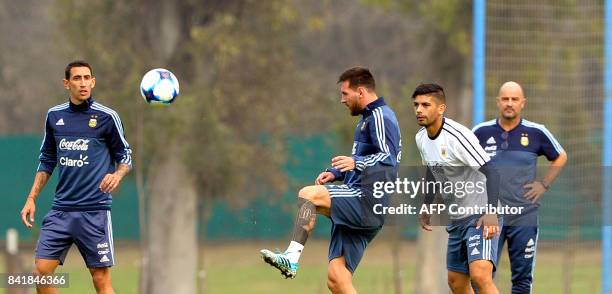 Argentina's forward Lionel Messi kicks the ball next to teammates midfielders Ever Banega and Angel Di Maria, during a training session in Ezeiza,...