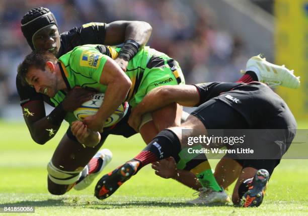 Nic Groom of Northampton Saints is tackled by Schalk Brits and Maro Itoje of Saracens during the Aviva Premiership match between Saracens and...