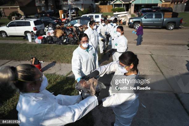 Members of Jehovah's Witnesses help a friend clean up their home after flood water inundated it, as the family begins the process of rebuilding after...