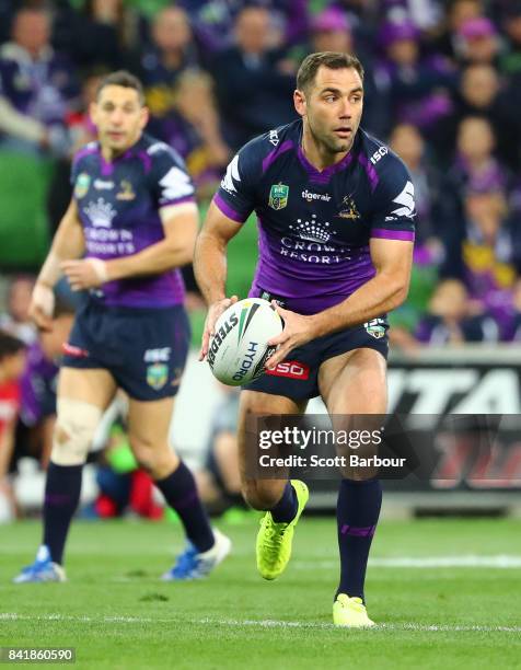 Cameron Smith of the Storm runs with the ball as Billy Slater looks on during the round 26 NRL match between the Melbourne Storm and the Canberra...