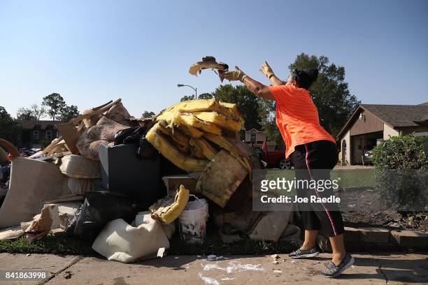 Regina Perry throws out wet sheetrock as she cleans out of her home that was inundated with water as she begins the process of rebuilding after...