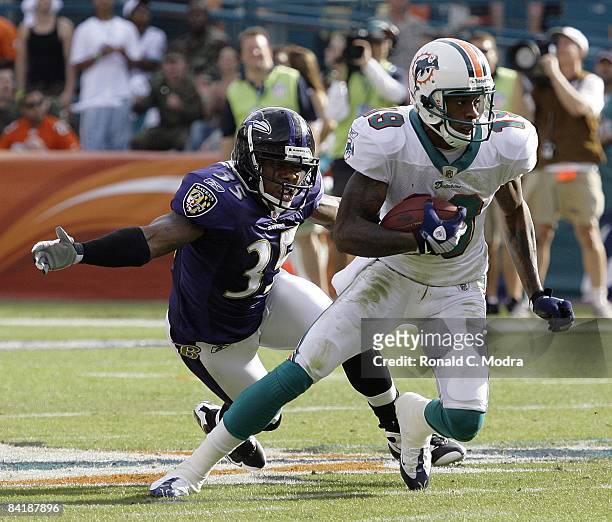 Ted Ginn Jr. #19 of the Miami Dolphins carries the ball as Corey Ivy of the Baltimore Ravens chases him during the AFC Wild Card Game at Dolphin...