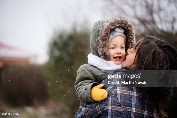 smiling baby girl and mother in winter park - kid in winter coat stock pictures, royalty-free photos & images