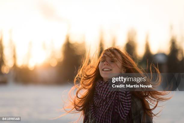 long red hair woman flipping hair in the air - winter coats stock-fotos und bilder