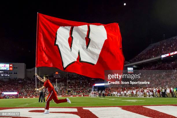 Wisconsin Badger cheerleader carries a flag across the end zone after scoring a touchdown durning an college football game between the Utah State...