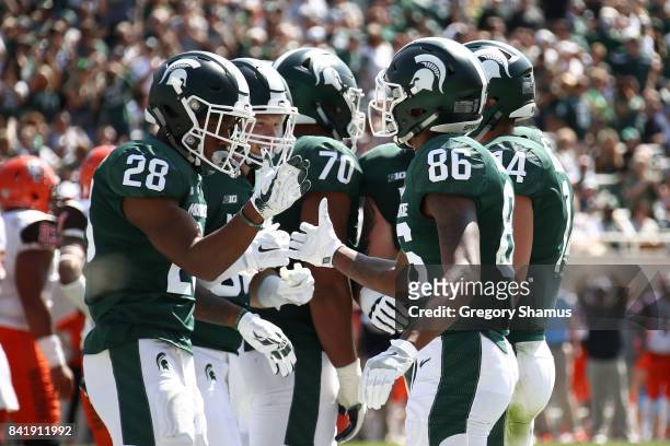 Madre London of the Michigan State Spartans celebrates a first half touchdown with Trishton Jackson while playing the Bowling Green Falcons at...