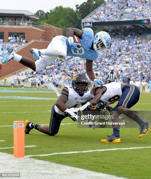 Jordon Brown of the North Carolina Tar Heels hurdles Derron Brown and Marloshawn Franklin Jr. #18 of the California Golden Bears and into the end...