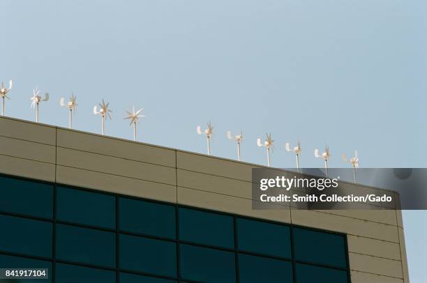 Line of small wind generators is installed at the top of an office building, generating green energy for the building, in the Silicon Valley, Santa...