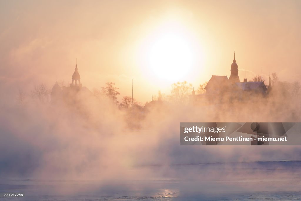 A freezing winter morning in Helsinki: sun coming up behind the mist rising from the frozen sea