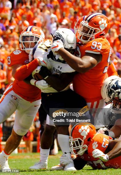 Tailback Will Matthews of the Kent State Flashes is taken down by safety Tanner Muse and defensive tackle Sterling Johnson of the Clemson Tigers of...