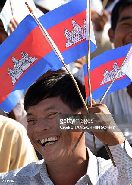 Man holds national flags during a People's Party ceremony marking the 30th anniversary of the fall of the Khmer Rouge regime at the National Stadium...