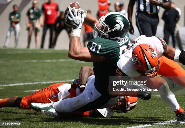 Matt Sokol of the Michigan State Spartans battles in for a second half touchdown past a hit by Ben Hale of the Bowling Green Falcons at Spartan...