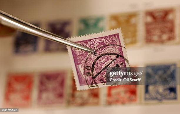 Stamp dealer uses a pair of tweezers to hold a rare stamp for sale at the Strand Stamp Show in the Royal National Hotel on January 7, 2008 in London,...