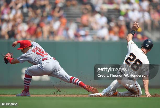 Kolten Wong of the St. Louis Cardinals stretches at second base to get the put out on Buster Posey of the San Francisco Giants in the bottom of the...