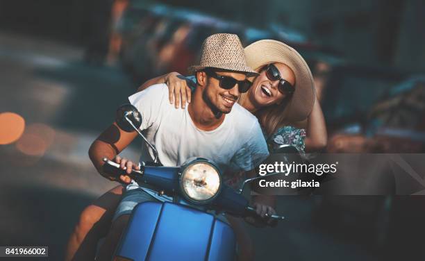 pareja en una moto scooter conducción por las calles. - holiday scooter fotografías e imágenes de stock